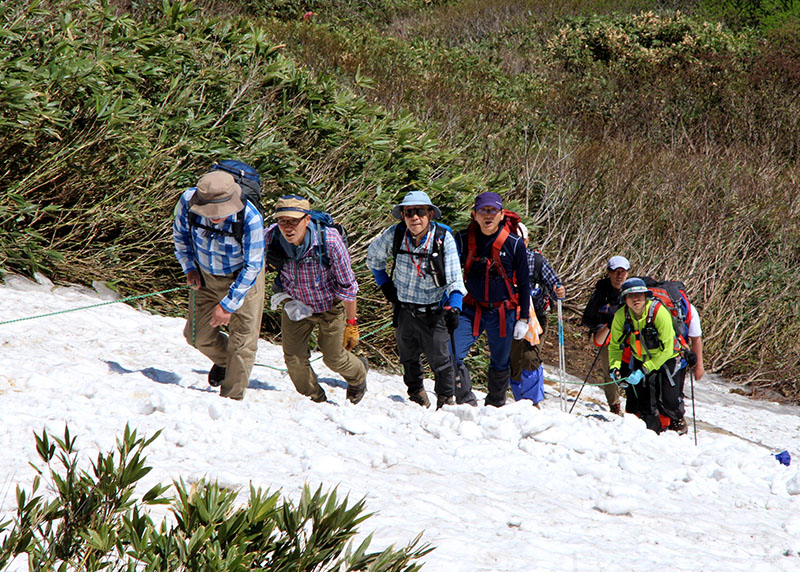 牛形山の頂を目指して雪渓を登る登山者たち